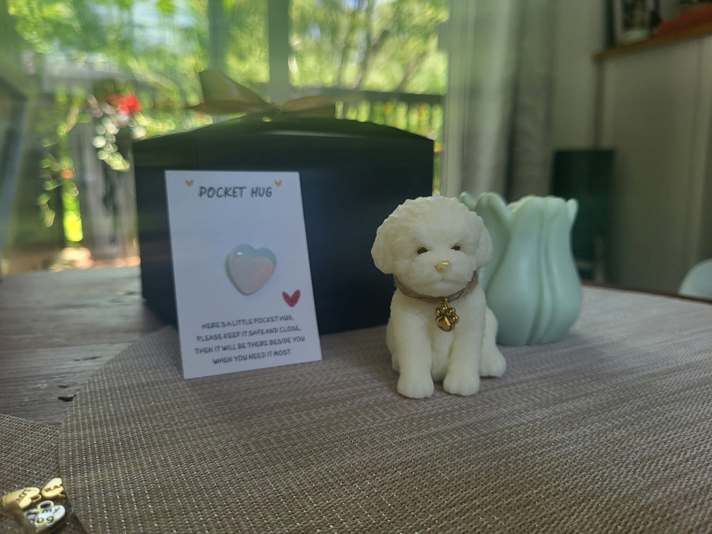 Small white dog figurine with a 'Pocket Hug' card on a table.