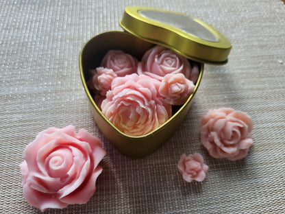 Heart-shaped gold tin with pink rose-shaped objects on a textured surface