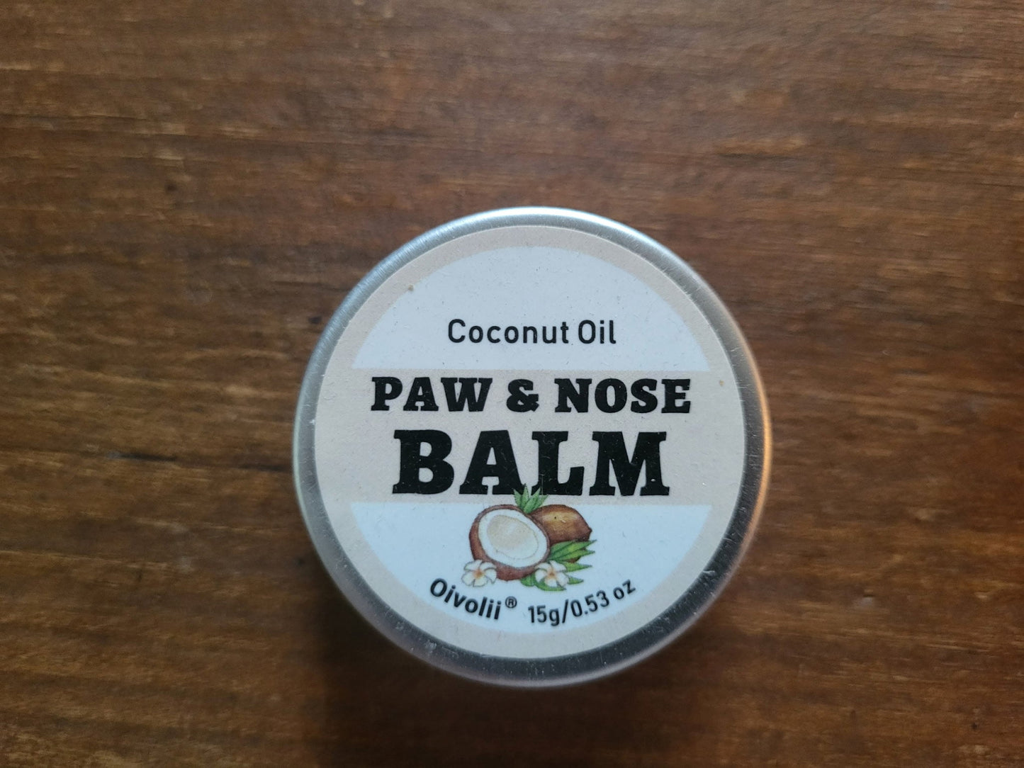Paw and nose balm container with coconut oil label on a wooden surface